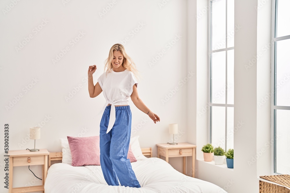 Young blonde woman dancing on bed at bedroom Young blonde woman dancing on bed at bedroom