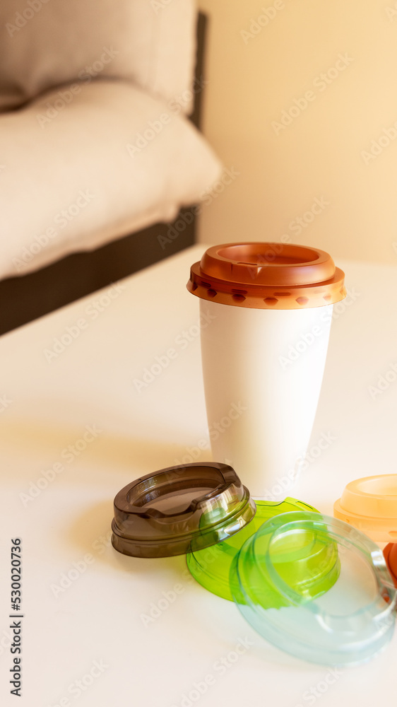a coffee in a plastic cup on the table with lids of different colors a coffee in a plastic cup on the table with lids of different colors