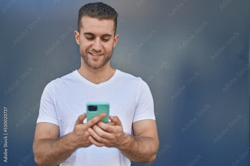 Young caucasian man smiling confident using smartphone over isolated grey background Young caucasian man smiling confident using smartphone over isolated grey background