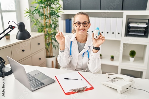 Wallpaper Mural Young doctor woman wearing uniform and stethoscope smiling happy pointing with hand and finger to the side Torontodigital.ca