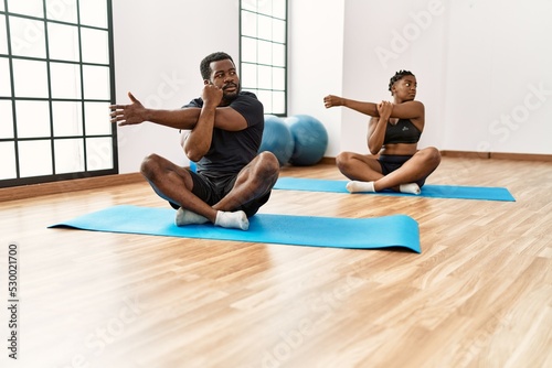 Young african american sporty couple training yoga at sport center.
