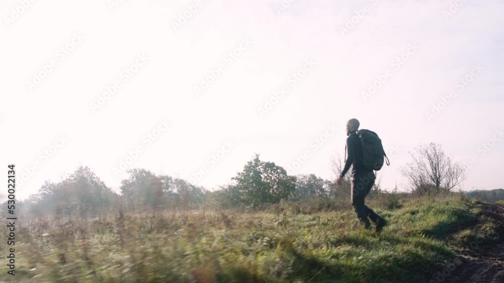 Man Tourist with Backpack Hikes in the Forest Through Tall Grass Meadow Man Tourist with Backpack Hikes in the Forest Through Tall Grass Meadow