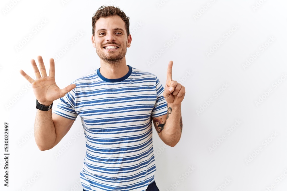 Handsome young man standing over isolated background showing and pointing up with fingers number six while smiling confident and happy. Handsome young man standing over isolated background showing and pointing up with fingers number six while smiling confident and happy.
