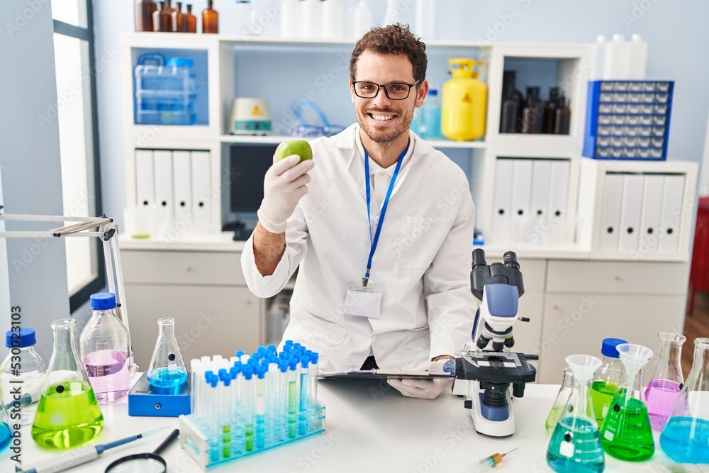 Young hispanic man scientist holding apple at laboratory Young hispanic man scientist holding apple at laboratory