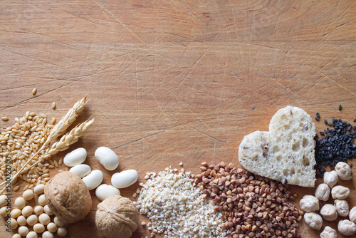 Whole grains products, groats, nuts, legumes, seeds on wooden background, healthy diet concept