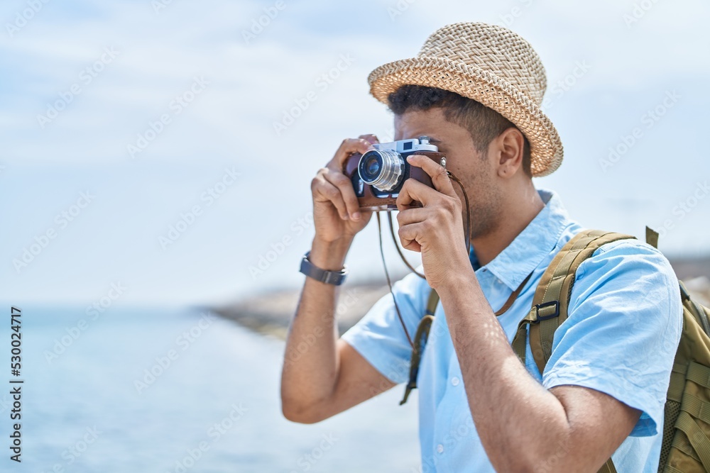 Obraz premium African american man tourist using vintage camera at seaside