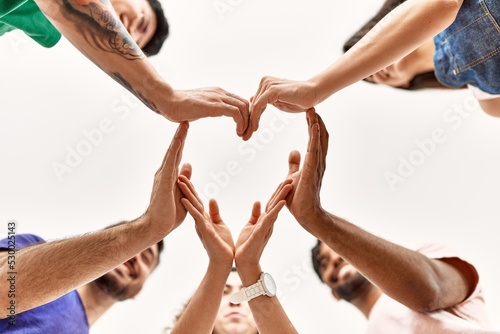 Group of young friends with hands together doing heart symbol.
