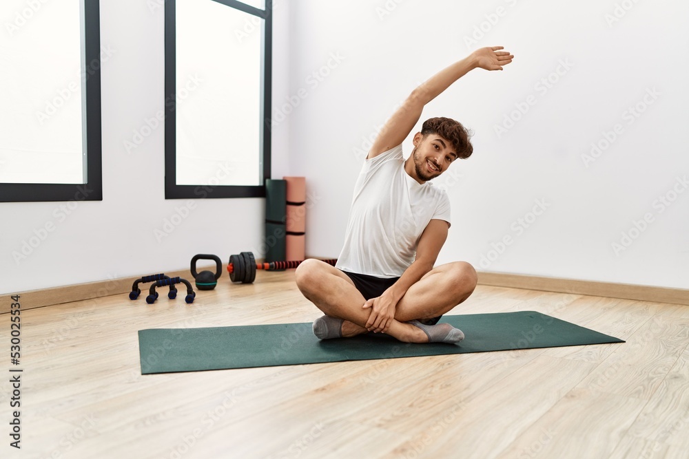 Fototapeta premium Young arab man smiling confident stretching at sport center