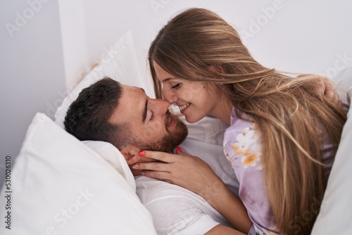 Man and woman couple lying on bed kissing at bedroom