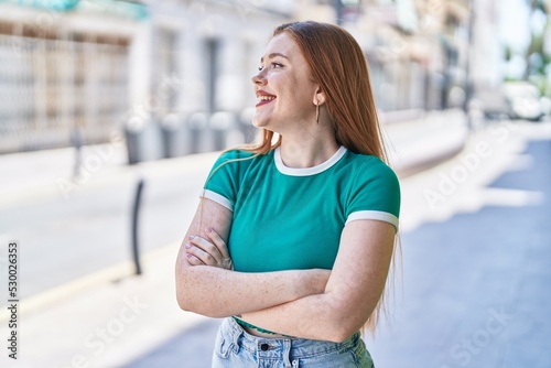 Fototapeta Naklejka Na Ścianę i Meble -  Young redhead woman standing with arms crossed gesture at street