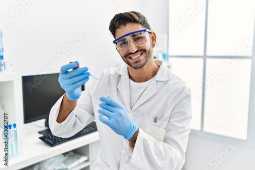 Handsome hispanic man working as scientific holding test tube at laboratory
