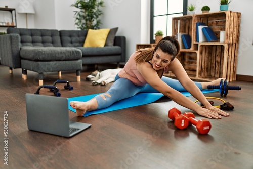 Young woman smiling confident having online stretching class at home