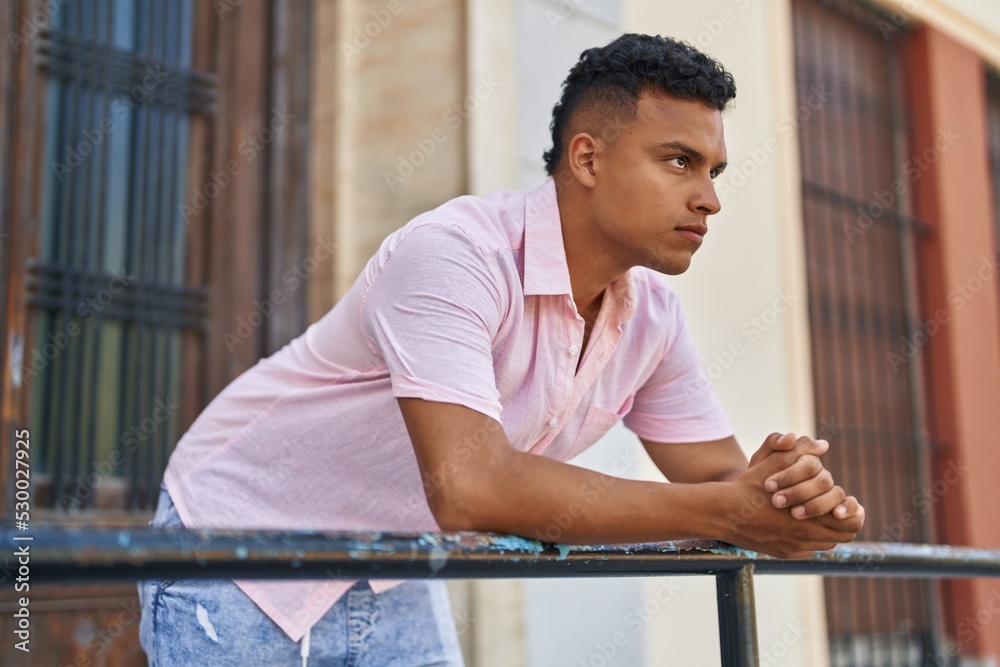 Young latin man with relaxed expression leaning on balustrade at street Young latin man with relaxed expression leaning on balustrade at street