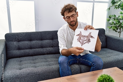 Young hispanic man doing rorschach test at psychology session at clinic