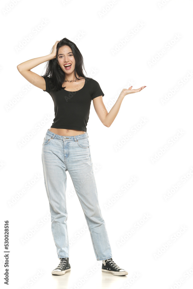 Young excited woman in jeans and shirt, advetising product on her palm, front view on a white background Young excited woman in jeans and shirt, advetising product on her palm, front view on a white background