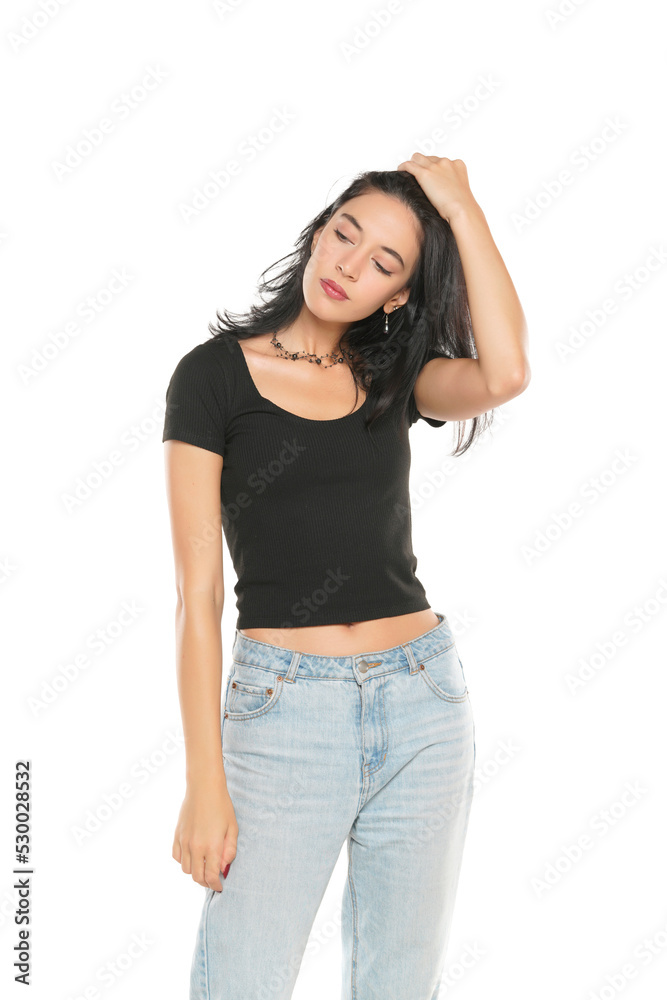 Young beautiful woman in loose jeans posing on white studio background Young beautiful woman in loose jeans posing on white studio background