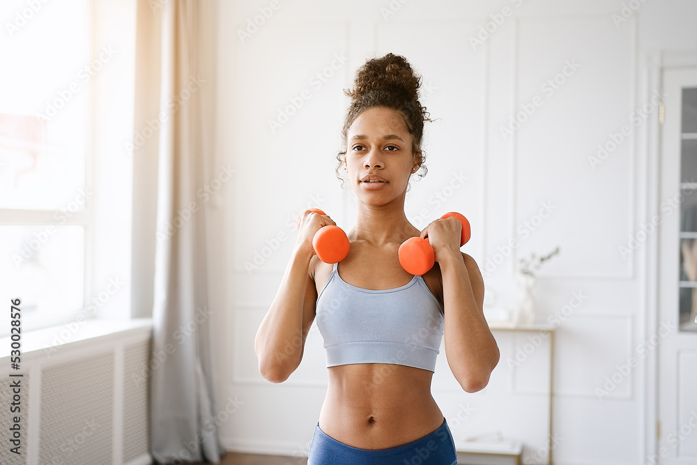 Home Sport. African american woman exercising with dumbbells and enjoying fitness and healthy lifestyle.	