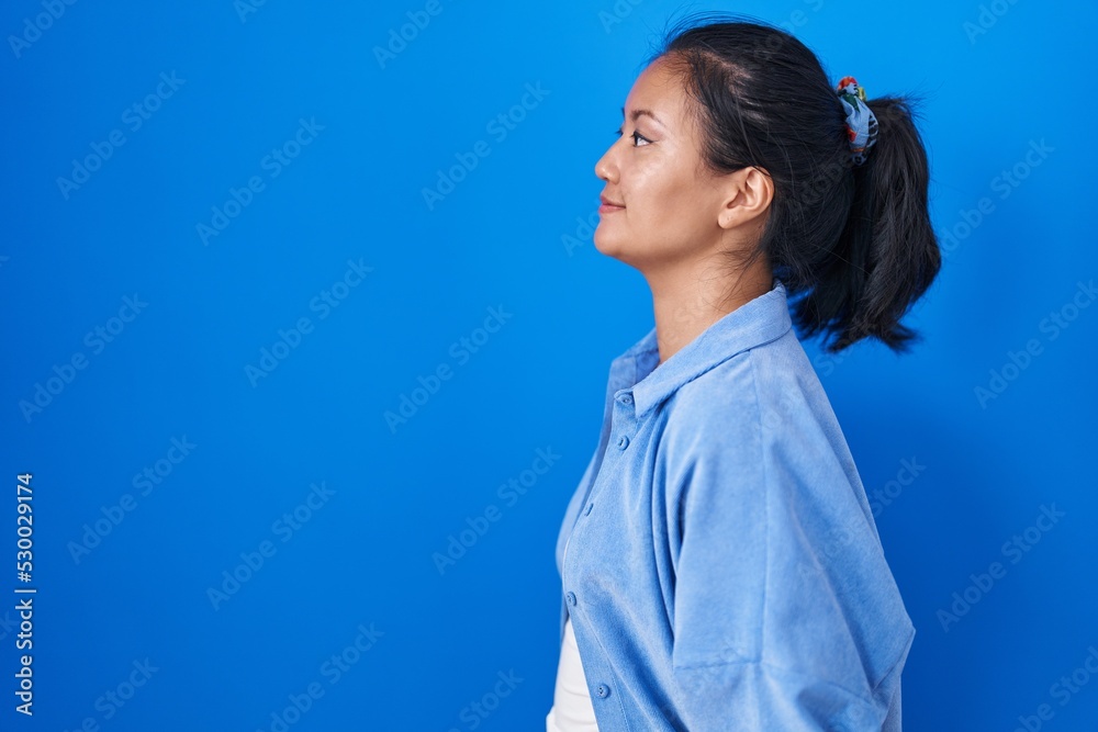 Asian young woman standing over blue background looking to side, relax profile pose with natural face and confident smile. Asian young woman standing over blue background looking to side, relax profile pose with natural face and confident smile.