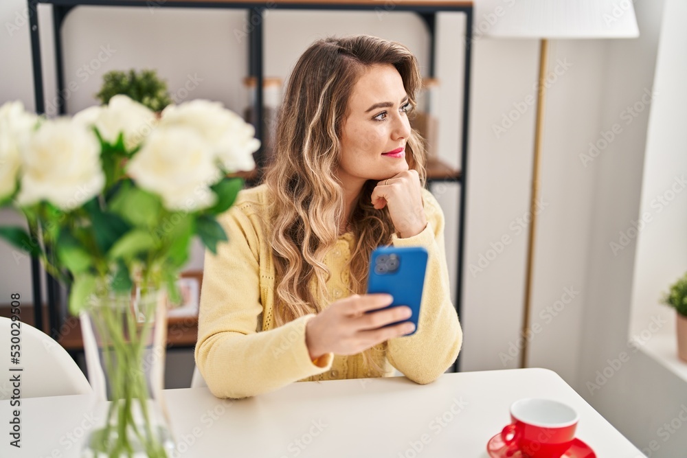 Young woman drinking coffee using smartphone at home Young woman drinking coffee using smartphone at home