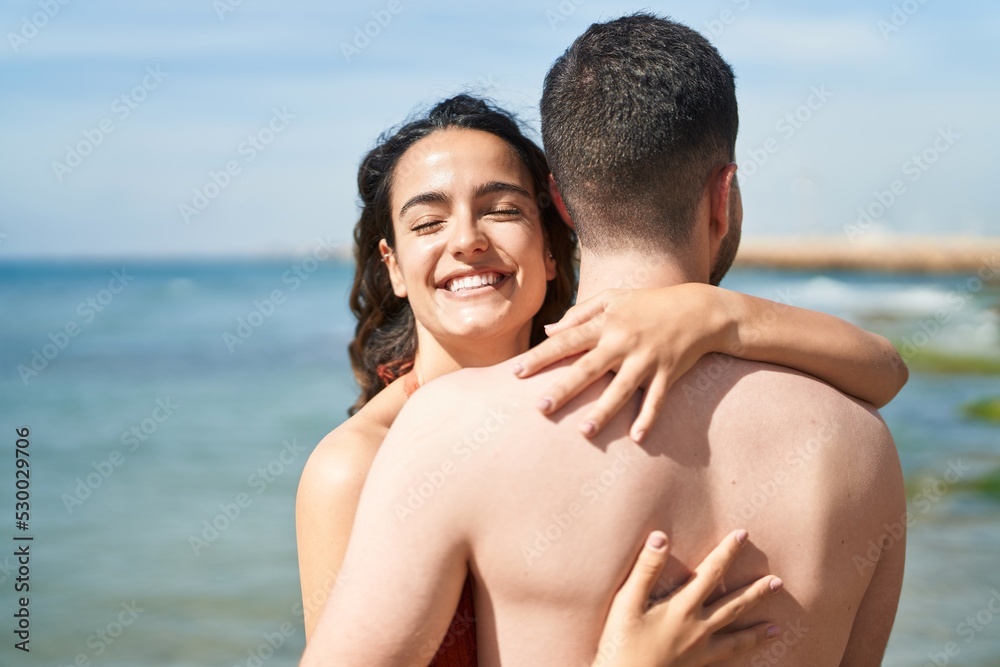 Young hispanic couple tourists wearing swimsuit hugging each other at seaside Young hispanic couple tourists wearing swimsuit hugging each other at seaside