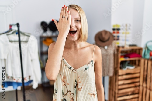 Fototapeta Naklejka Na Ścianę i Meble -  Young caucasian woman at retail shop covering one eye with hand, confident smile on face and surprise emotion.