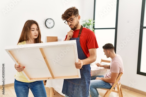 Group of people drawing sitting on the table. Man and woman concentrated looking to canvas at art studio.