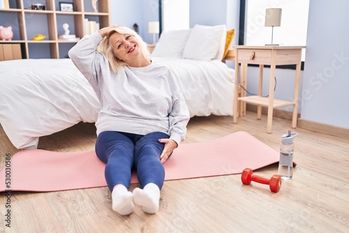 Middle age blonde woman smiling confident stretching at bedroom © Krakenimages.com
