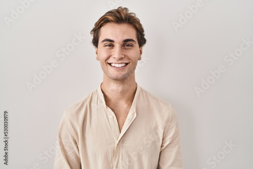 Young man standing over isolated background with a happy and cool smile on face. lucky person.