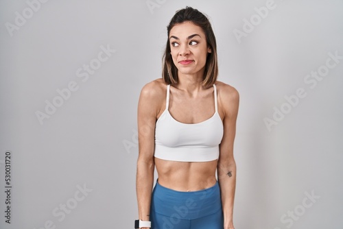 Hispanic woman wearing sportswear over isolated background smiling looking to the side and staring away thinking. © Krakenimages.com