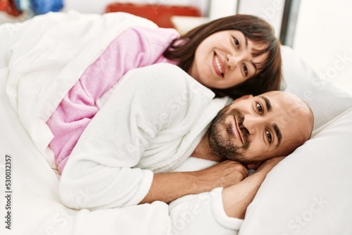 Young hispanic couple smiling happy lying on the bed at bedroom.