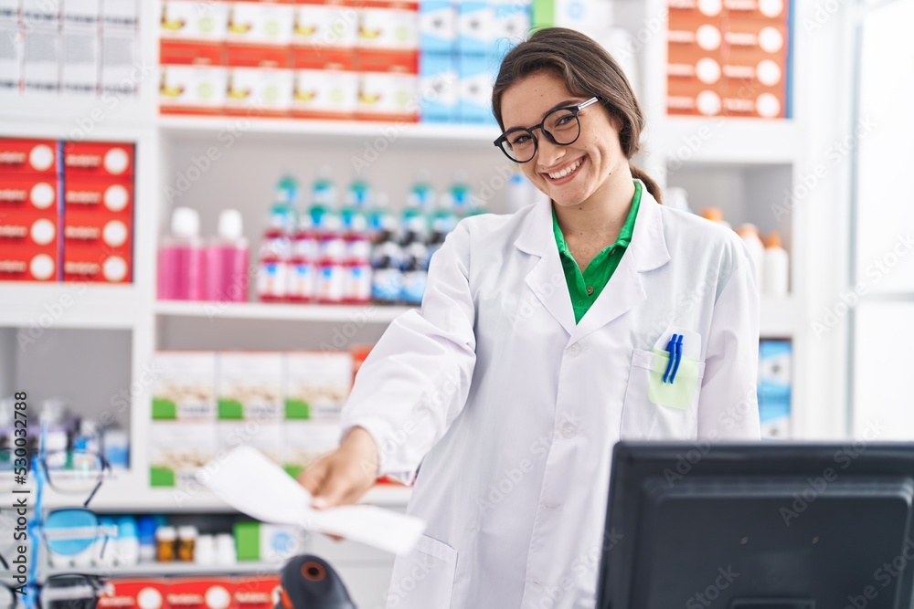 Young hispanic woman pharmacist smiling confident holding prescription paper at pharmacy