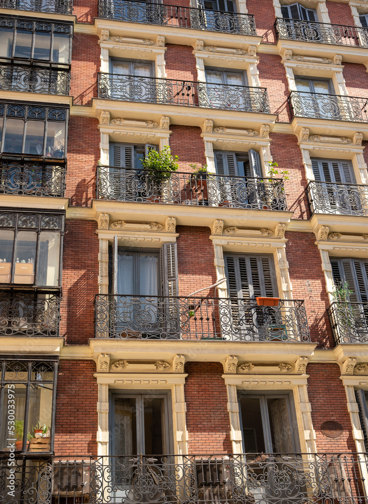 Typical windows and balconies in the Spanish city of Madrid under the hot setting sun.