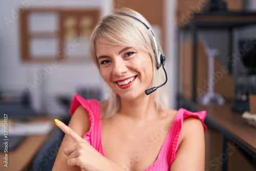 Young caucasian woman wearing call center agent headset smiling happy pointing with hand and finger to the side