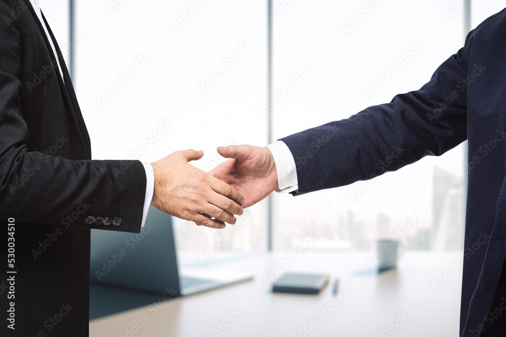 Two businessmen shake hands in sunny modern office, deal concept, close up