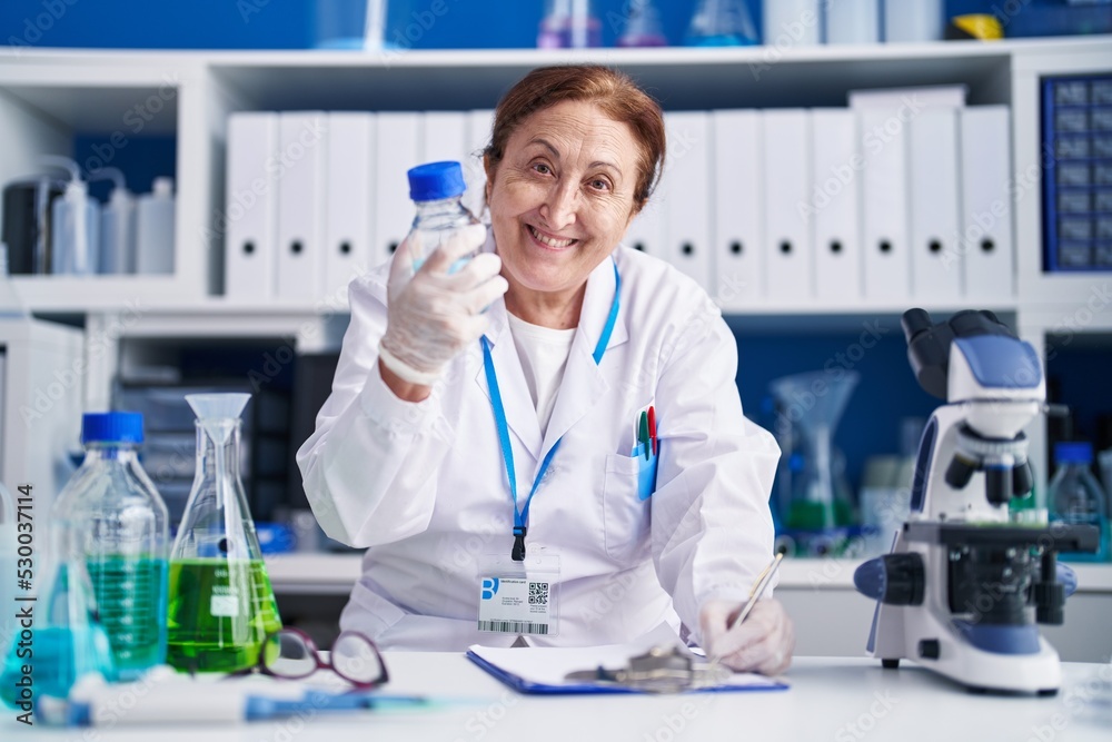 Senior woman scientist measuring liquid write on document at laboratory Senior woman scientist measuring liquid write on document at laboratory