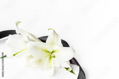 Mourning or funeral concept with white liles and black ribbon photo