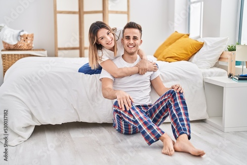 Man and woman couple hugging each other sitting on bed at bedroom