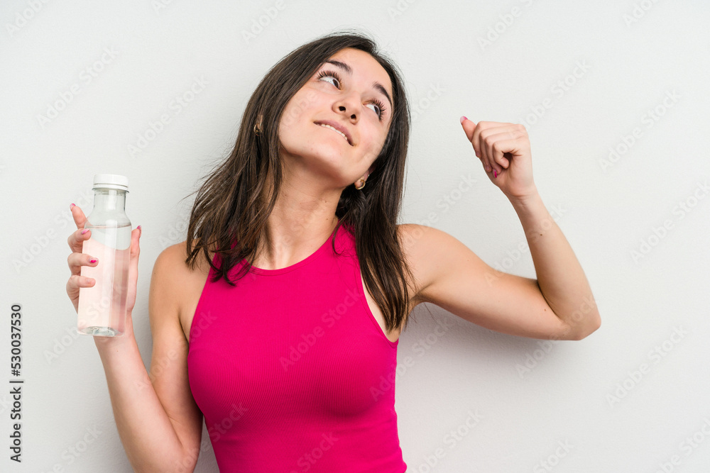 Young caucasian woman holding a bottle of water isolated on white background raising fist after a victory, winner concept. Young caucasian woman holding a bottle of water isolated on white background raising fist after a victory, winner concept.
