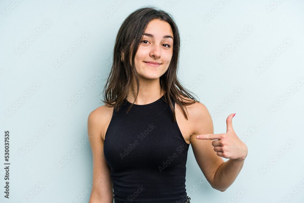 Young caucasian woman isolated on blue background person pointing by hand to a shirt copy space, proud and confident Young caucasian woman isolated on blue background person pointing by hand to a shirt copy space, proud and confident