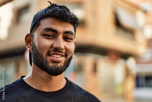 Young arab man smiling confident wearing cap at street