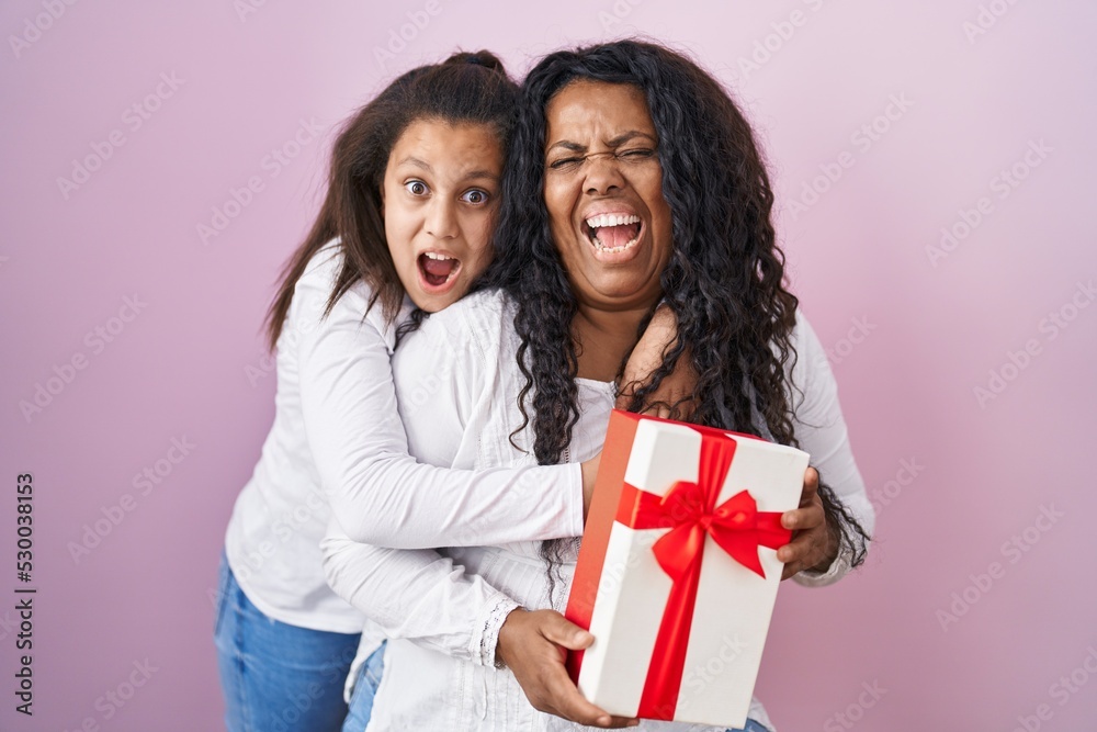 Mother and young daughter holding with presents celebrating crazy and amazed for success with open eyes screaming excited. Mother and young daughter holding with presents celebrating crazy and amazed for success with open eyes screaming excited.