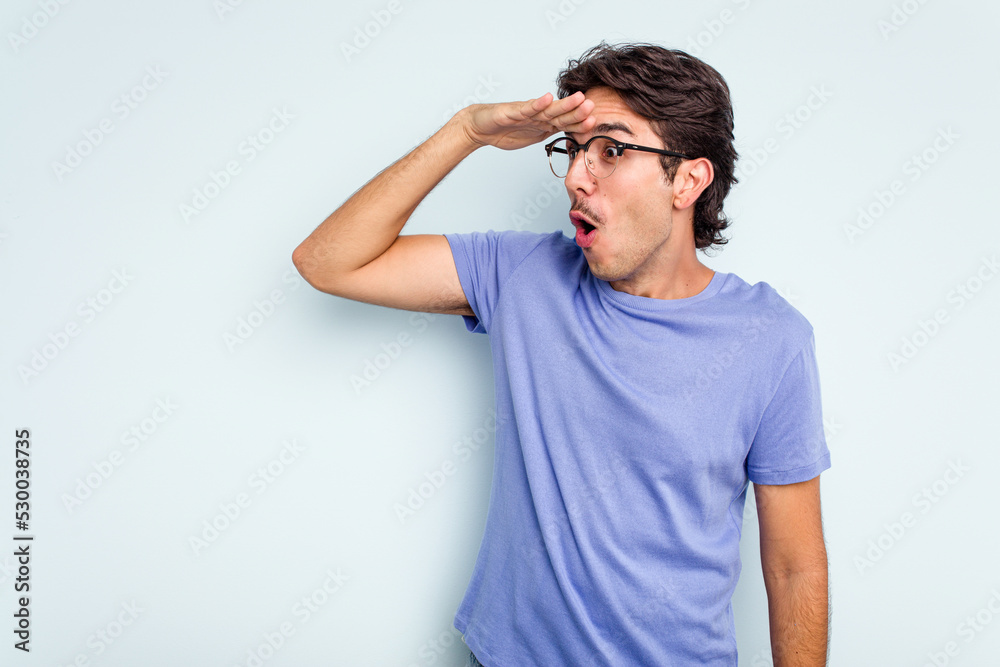 Young hispanic man isolated on blue background looking far away keeping hand on forehead. Young hispanic man isolated on blue background looking far away keeping hand on forehead.