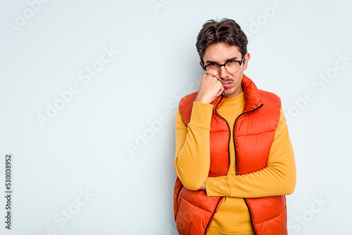 Young hispanic man isolated on blue background who feels sad and pensive, looking at copy space.