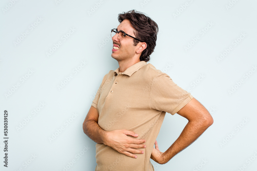 Obraz premium Young hispanic man isolated on blue background suffering a back pain.