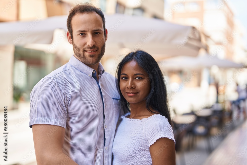 Man and woman interracial couple hugging each other at street Man and woman interracial couple hugging each other at street