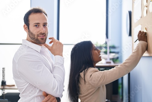 Man and woman business workers writing on cork board at office