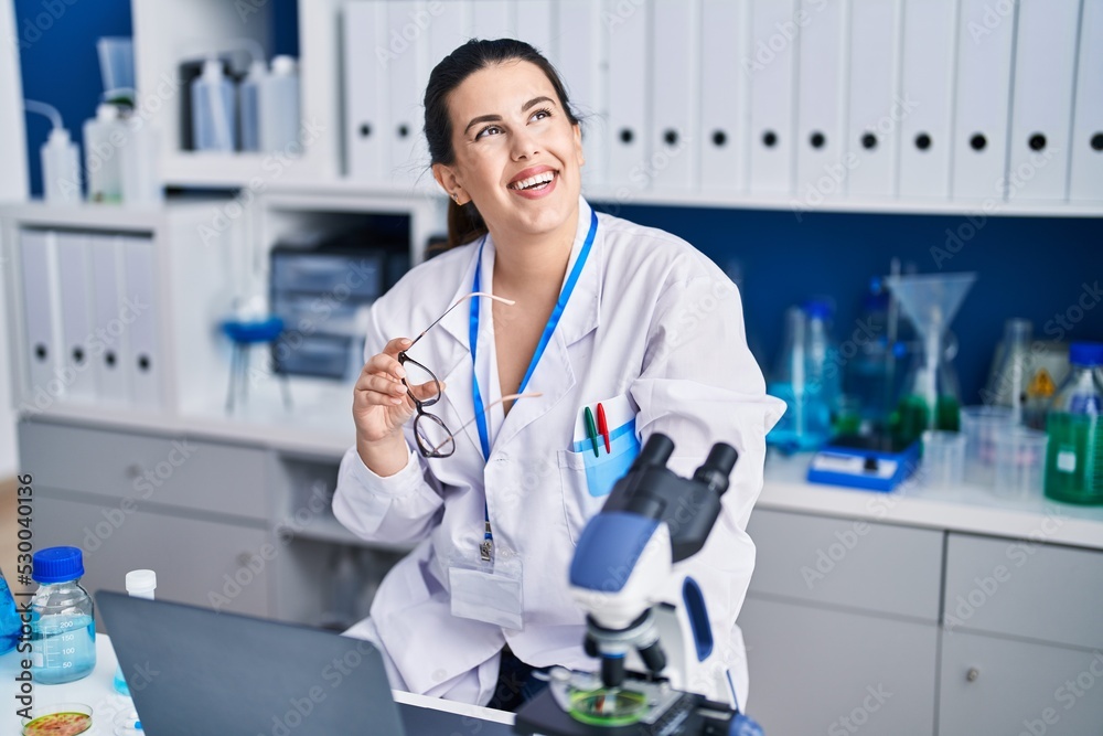 Young hispanic woman scientist using laptop working at laboratory