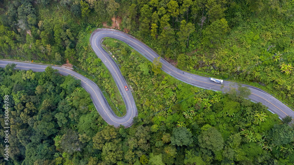 Aerial view of a hilltop road with beautiful green forests in Thailand. Aerial capture with drone.