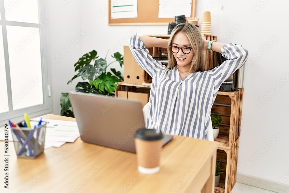 Young chinese woman smiling confident relaxed with hands on head at office