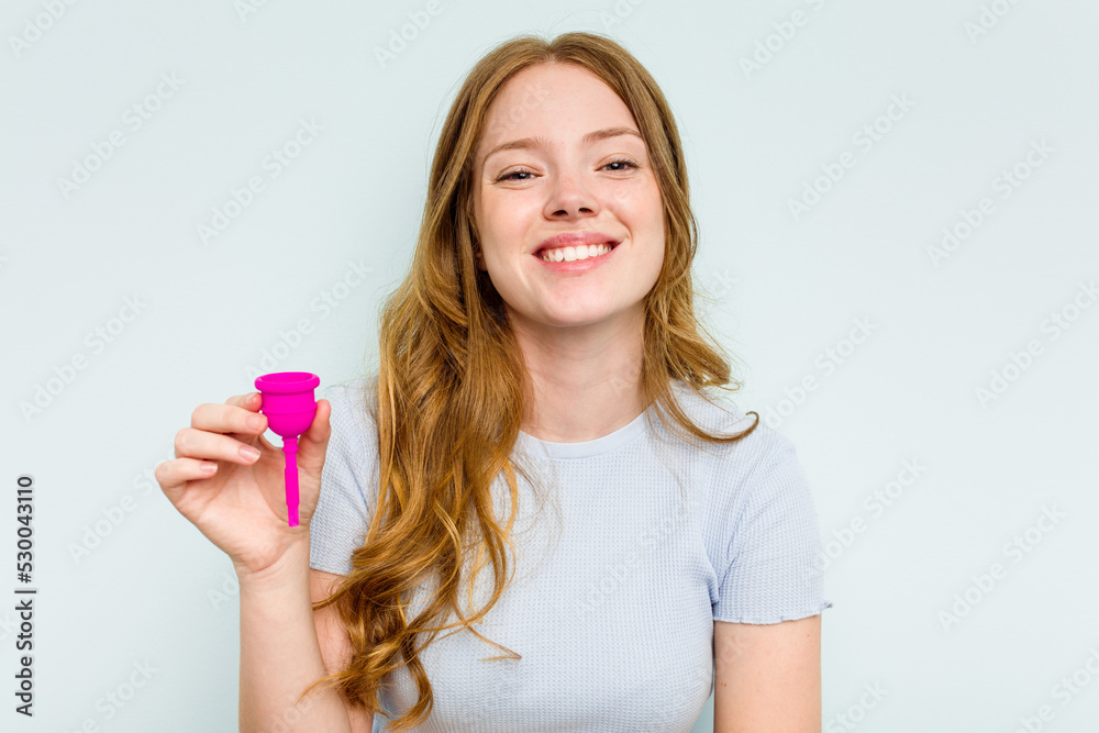 Young caucasian woman holding menstrual cup isolated on blue background laughing and having fun. Young caucasian woman holding menstrual cup isolated on blue background laughing and having fun.